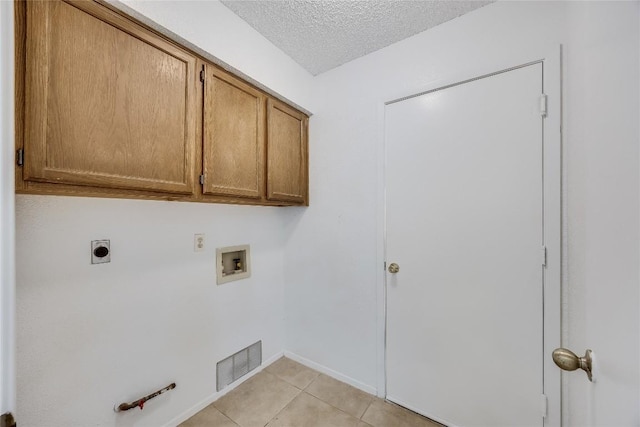 laundry area featuring hookup for a washing machine, a textured ceiling, light tile patterned flooring, visible vents, and cabinet space