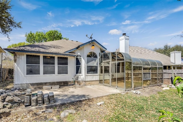 rear view of house with a patio area, roof with shingles, a chimney, fence, and a sunroom