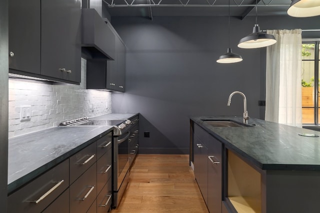 933 E 52nd St, Austin, TX 78751 - kitchen featuring stainless steel electric range, a sink, light wood-type flooring, backsplash, and a center island with sink