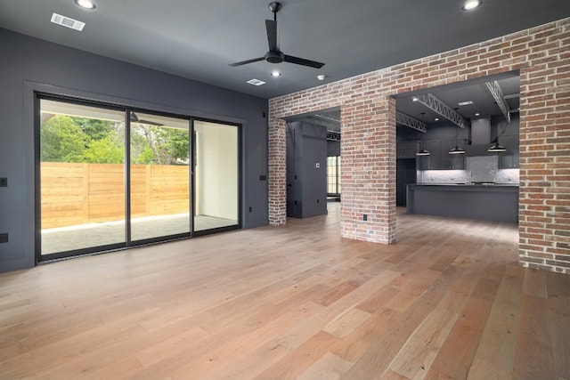 933 E 52nd St, Austin, TX 78751 - unfurnished living room with ornate columns, ceiling fan, light wood finished floors, brick wall, and recessed lighting