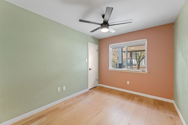 unfurnished room with baseboards, wood finished floors, a textured wall, and a ceiling fan