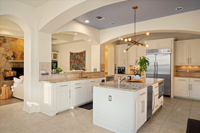 11801 Astoria Dr, Bee Cave, TX 78738 - kitchen with a sink, built in appliances, a center island with sink, backsplash, and light stone countertops