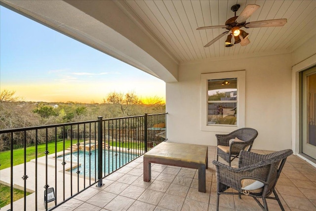 balcony with a pool with connected hot tub, a patio area, and a ceiling fan