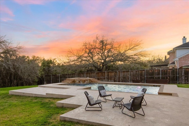 pool at dusk featuring a fenced backyard, a patio area, and a fenced in pool