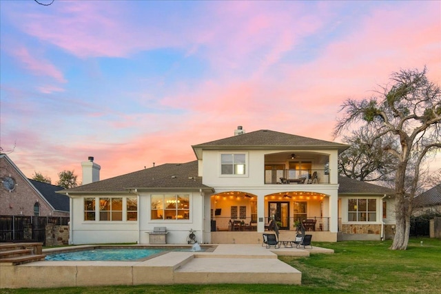 11801 Astoria Dr, Bee Cave, TX 78738 - back of property at dusk with ceiling fan, a patio area, a balcony, stucco siding, and a chimney