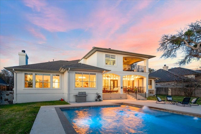 back of property with a fenced in pool, fence, a balcony, stucco siding, and a patio area
