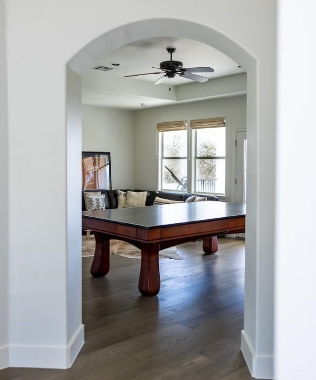 rec room featuring a ceiling fan, wood finished floors, arched walkways, baseboards, and visible vents