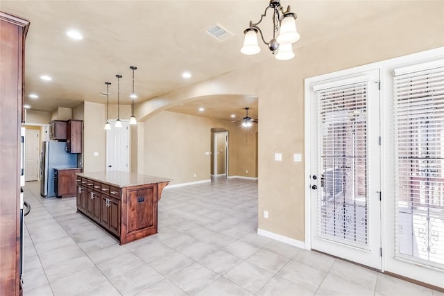 3519 Alexandrite Way, Round Rock, TX 78681 - kitchen featuring arched walkways, freestanding refrigerator, hanging light fixtures, a kitchen island, and baseboards