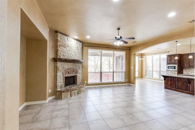 3519 Alexandrite Way, Round Rock, TX 78681 - unfurnished living room featuring a ceiling fan, a fireplace, light tile patterned floors, recessed lighting, and arched walkways