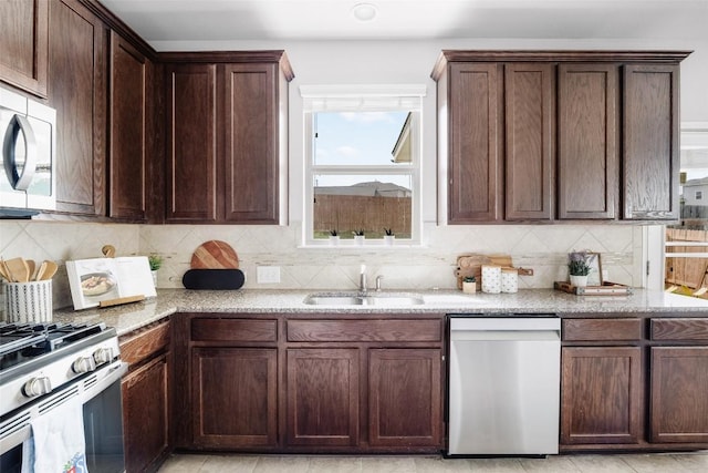 366 Eagle Brook Ln, Buda, TX 78610 - kitchen with dishwasher, stainless steel gas range oven, light stone counters, decorative backsplash, and dark brown cabinetry