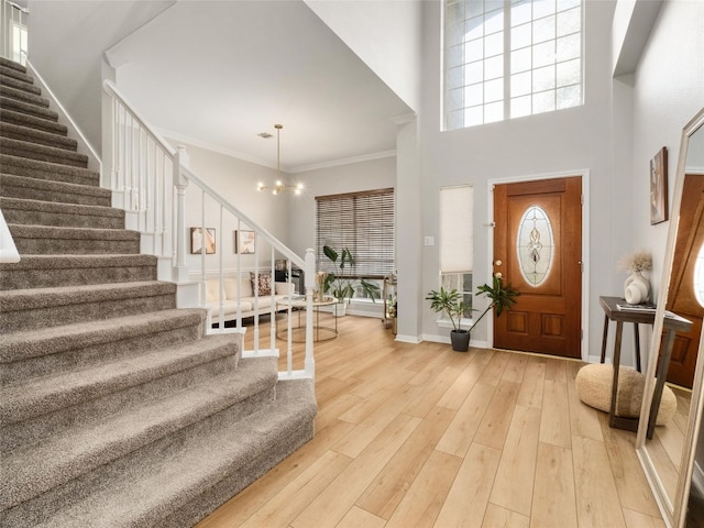 foyer entrance featuring stairs, ornamental molding, light wood-type flooring, and a wealth of natural light