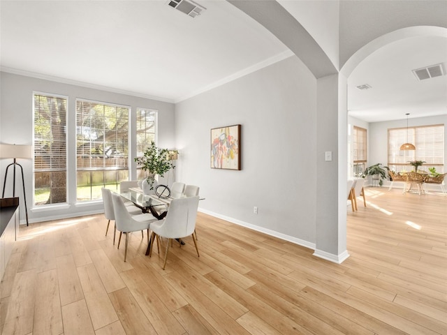dining area featuring light wood finished floors, visible vents, and arched walkways