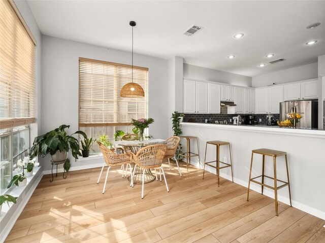 kitchen with freestanding refrigerator, tasteful backsplash, under cabinet range hood, and visible vents