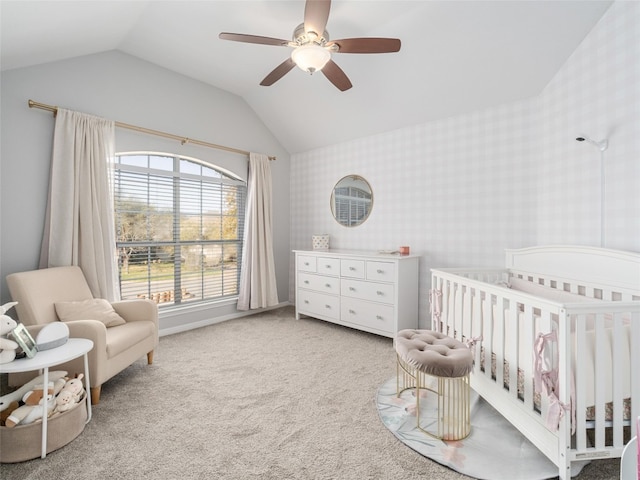 bedroom featuring ceiling fan, wallpapered walls, light carpet, lofted ceiling, and a nursery area