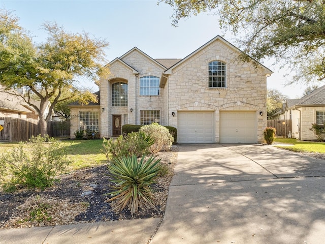 french country inspired facade with a front yard, stone siding, concrete driveway, fence, and an attached garage