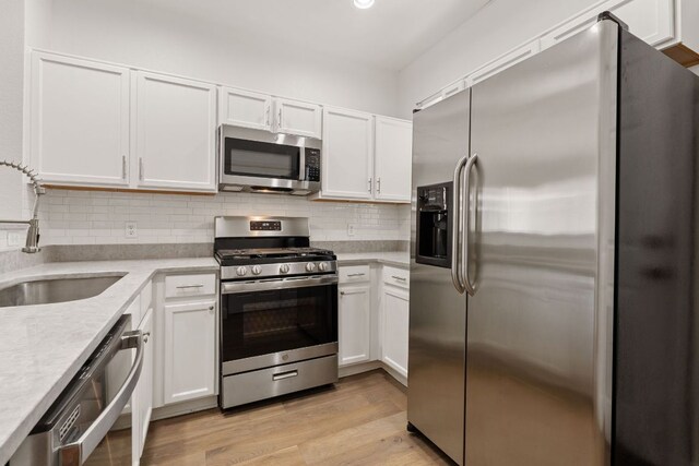 210 Crockett Loop, Georgetown, TX 78633 - kitchen featuring stainless steel appliances, a sink, white cabinetry, backsplash, and light wood-style floors