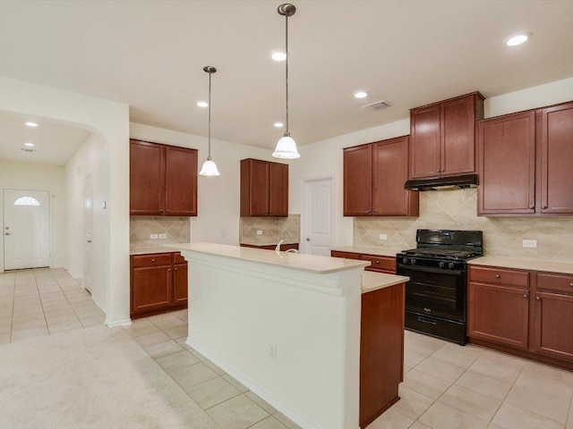 1501 Uhland Dr, Leander, TX 78641 - kitchen with black gas range, under cabinet range hood, light tile patterned flooring, light countertops, and decorative backsplash