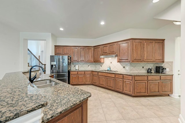 13229 Country Trails Ln, Austin, TX 78732 - kitchen with stainless steel appliances, tasteful backsplash, under cabinet range hood, stone countertops, and brown cabinets