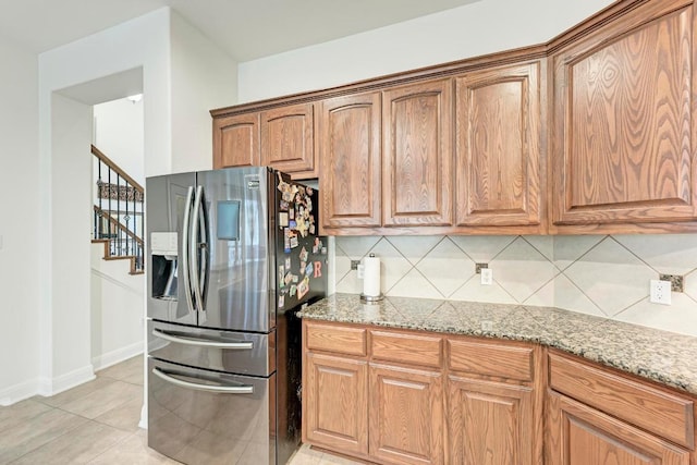 13229 Country Trails Ln, Austin, TX 78732 - kitchen with stainless steel refrigerator with ice dispenser, tasteful backsplash, light stone counters, and brown cabinets