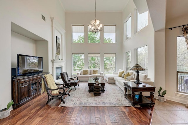 13229 Country Trails Ln, Austin, TX 78732 - living area with a towering ceiling, a chandelier, a fireplace, crown molding, and wood finished floors