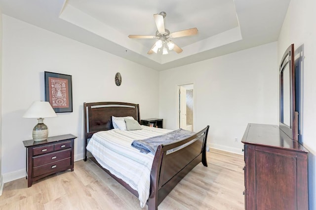 13229 Country Trails Ln, Austin, TX 78732 - bedroom featuring a tray ceiling, light wood-type flooring, a ceiling fan, and connected bathroom
