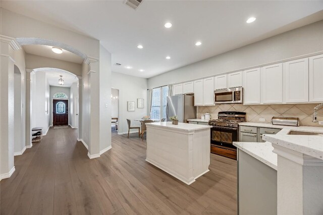 2974 Overland St, Round Rock, TX 78681 - kitchen with stainless steel appliances, decorative columns, arched walkways, backsplash, and a kitchen island