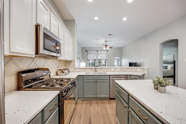 2974 Overland St, Round Rock, TX 78681 - kitchen featuring appliances with stainless steel finishes, gray cabinetry, light wood-type flooring, arched walkways, and ceiling fan