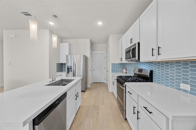 1512 Honaker Way, Leander, TX 78641 - kitchen with stainless steel appliances, light wood-type flooring, light countertops, tasteful backsplash, and pendant lighting