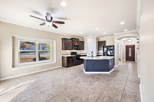 kitchen featuring ceiling fan, tasteful backsplash, arched walkways, a sink, and black appliances