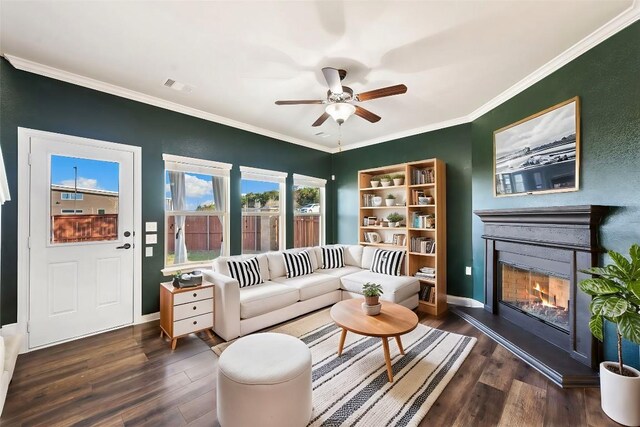 sitting room with ornamental molding, visible vents, a ceiling fan, a glass covered fireplace, and wood finished floors