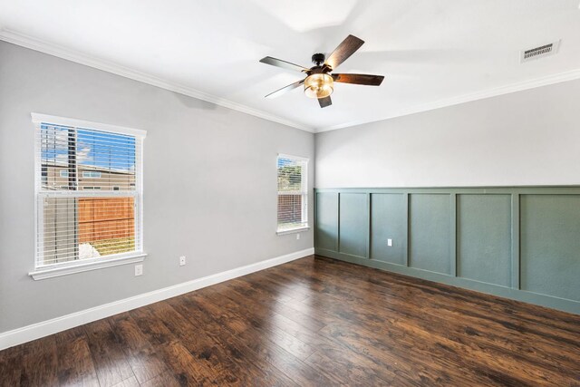 spare room with crown molding, dark wood-style flooring, baseboards, visible vents, and a ceiling fan