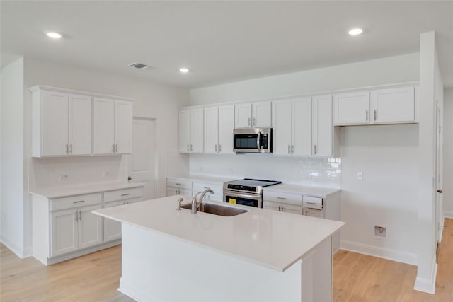 kitchen with visible vents, appliances with stainless steel finishes, light wood-style flooring, a sink, and white cabinetry