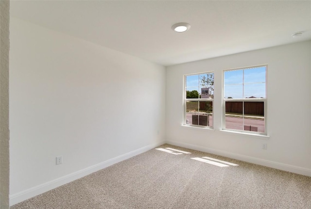 carpeted empty room featuring baseboards