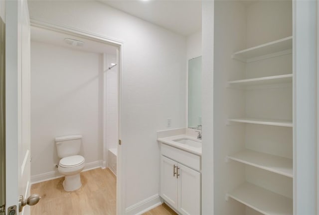 bathroom featuring toilet, washtub / shower combination, wood finished floors, and vanity