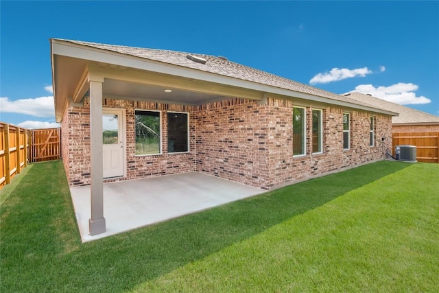 rear view of house with a fenced backyard, a patio, a lawn, and brick siding
