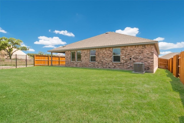 back of house featuring brick siding, a fenced backyard, central AC, and a yard