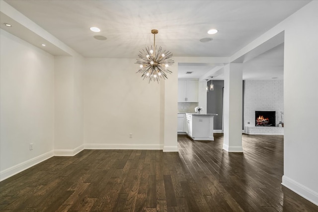 306 Briarwood Trl, Austin, TX 78746 - unfurnished living room featuring a fireplace, baseboards, dark wood-style floors, a chandelier, and recessed lighting