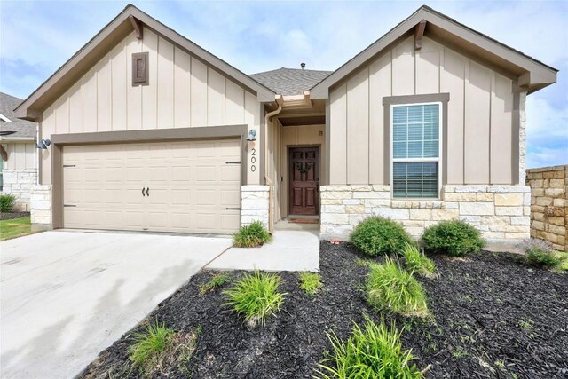 200 Isabella Way, Liberty Hill, TX 78642 - view of front of house featuring board and batten siding, stone siding, an attached garage, driveway, and roof with shingles