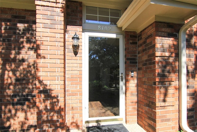 doorway to property featuring brick siding