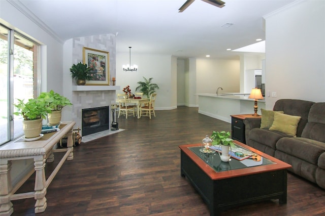 living room with crown molding, wood finished floors, baseboards, an inviting chandelier, and recessed lighting