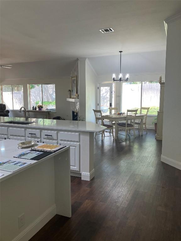8102 Davis Mountain Pass, Austin, TX 78726 - kitchen with a chandelier, white cabinetry, dark wood-style floors, light countertops, and decorative light fixtures