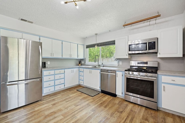 5304 Harvest Ln, Austin, TX 78745 - kitchen featuring stainless steel appliances, a sink, a textured ceiling, light countertops, and light wood finished floors