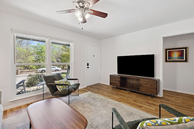 living room with baseboards, ceiling fan, and wood finished floors