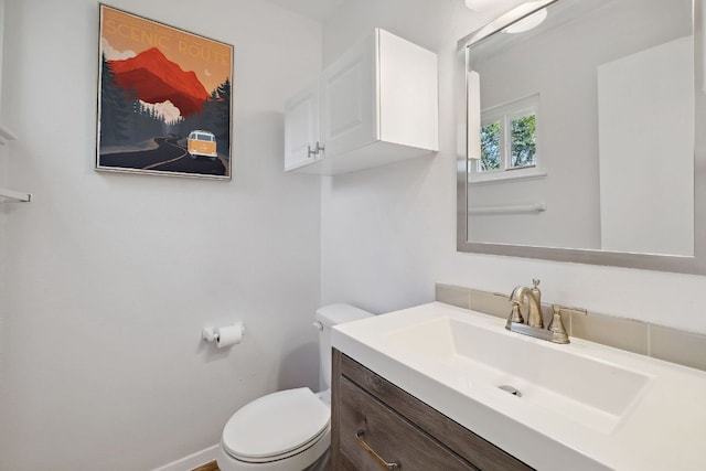 half bathroom featuring baseboards, toilet, and vanity