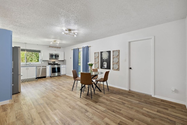 dining room with light wood finished floors, baseboards, and a textured ceiling