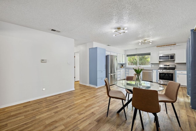 5304 Harvest Ln, Austin, TX 78745 - dining area featuring light wood-style floors, baseboards, and a textured ceiling