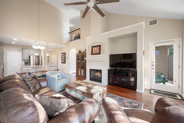 7901 SW Pkwy Unit 21, Austin, TX 78735 - living room featuring a ceiling fan, arched walkways, dark wood-type flooring, a warm lit fireplace, and high vaulted ceiling