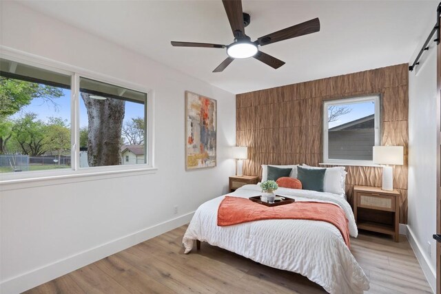 1113 Plymouth Dr, Austin, TX 78758 - bedroom with a barn door, baseboards, light wood finished floors, and a ceiling fan