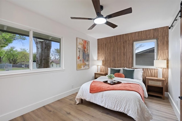 1113 Plymouth Dr, Austin, TX 78758 - bedroom featuring a barn door, light wood-style floors, and ceiling fan