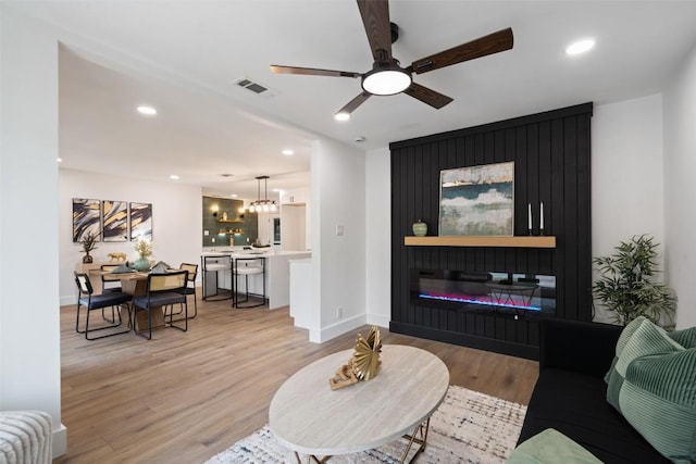 1113 Plymouth Dr, Austin, TX 78758 - living area featuring light wood-style flooring, recessed lighting, ceiling fan, a glass covered fireplace, and a chandelier
